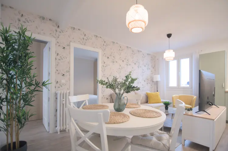 Salón comedor con mesa redonda, sillas blancas y plantas