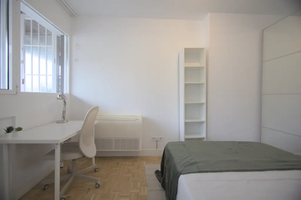 Dormitorio con escritorio, silla de trabajo y armario blanco