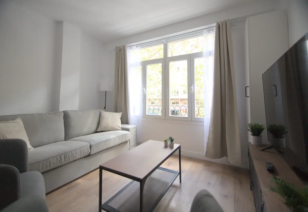 Salón con sofá, mesa de centro y ventanales