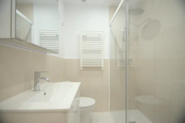 Baño con plato de ducha, mampara y lavabo con mueble