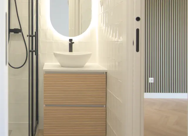 Baño con lavabo sobre encimera de madera y espejo iluminado
