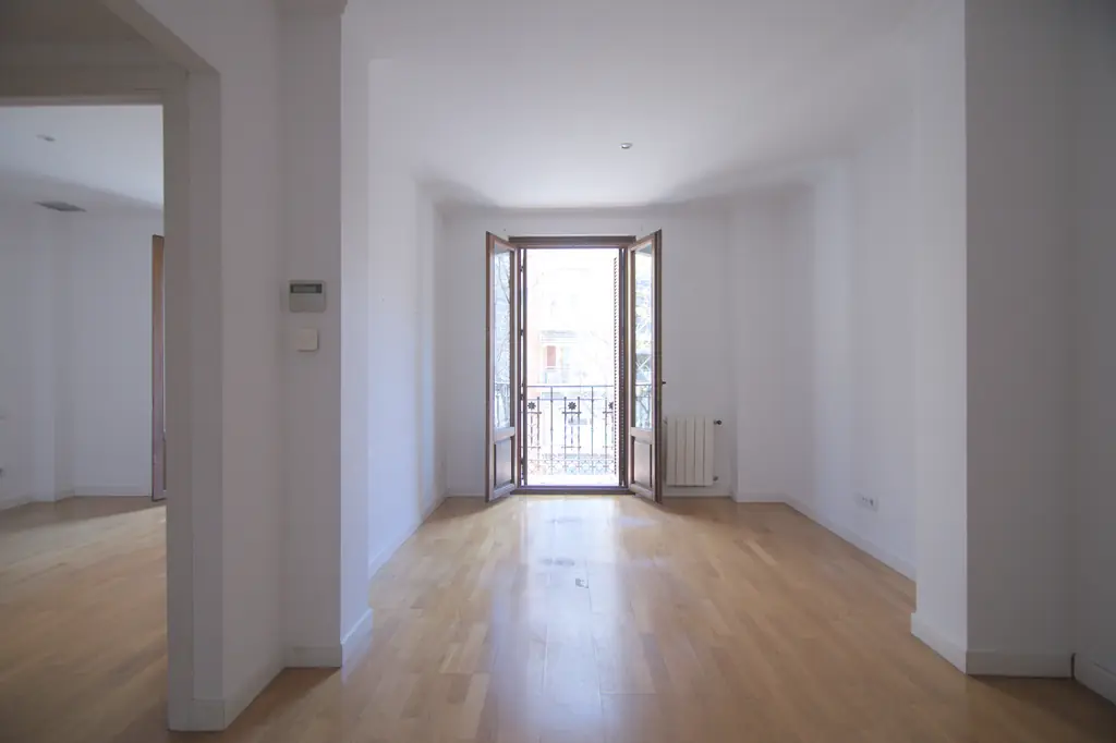 Salón luminoso con suelo de madera y balcón de un piso completo
