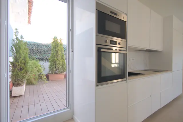 Entrada con salida a terraza y cocina blanca integrada
